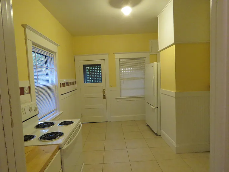 Second room of kitchen with stove, refrigerator and backyard access.
