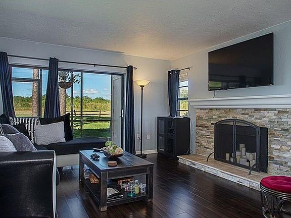 Living area with updated fireplace and TV above mantel. A better view of the open area in the back with screened in lanai for a beautiful, peaceful setting. The TV is included.
