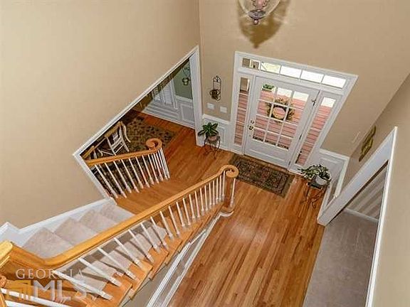 Beautiful transom front door with sidelights open into foyer with hardwood floors, picture mold wain