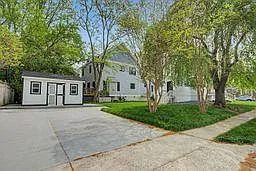 Wide concrete driveway with side access and a detached structure, plus a grassy yard with mature trees. - S Kent St