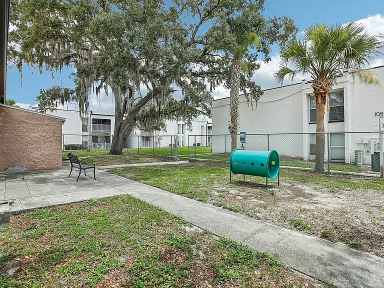 Charming outdoor space with a bench, lush trees, and a playful area for pets, perfect for relaxation and enjoyment.