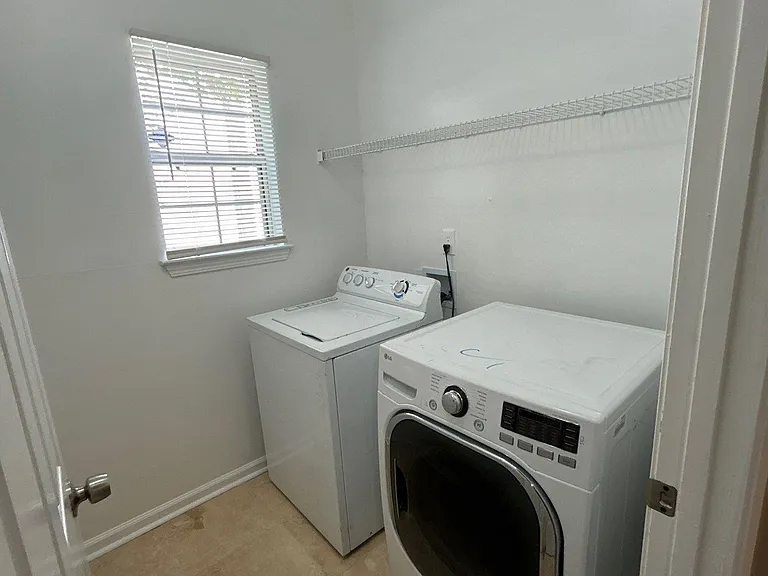 Dedicated laundry room with washer and dryer, overhead wire shelving, and a window for natural light.