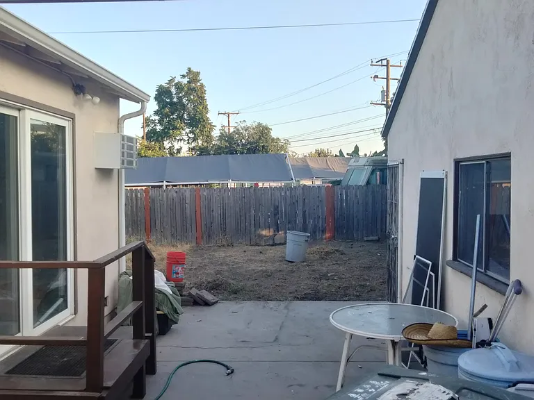 Patio between the house and garage. There is a large security gate in front of the garage that has access to this area, it is located to the right of the green trash can in the picture