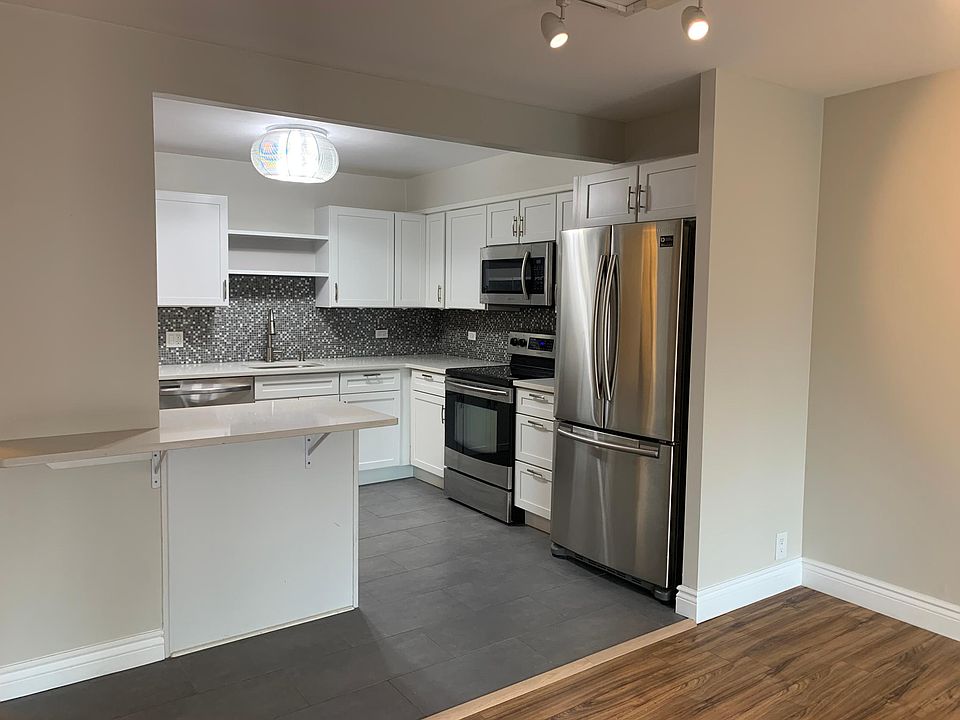 Large open kitchen with white shaker cabinets, open shelves above the sink and seating at island.