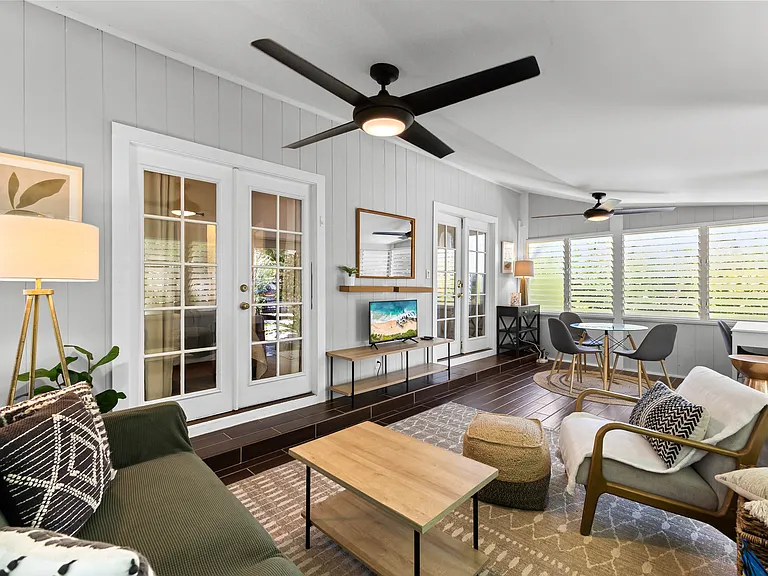 Enclosed lanai adds additional living space, a futon sofa, chair, TV, small dining set for 3-4, and a desk. Two large fans and lots of windows keep this area cool.