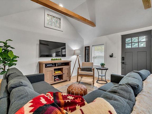 Open concept living & dining area featuring 55" Smart TV, gas fireplace, sectional seating and table for comfortable in home dining for 4. Entry area with bench & wall hooks for convenient shoe, coat & hat.