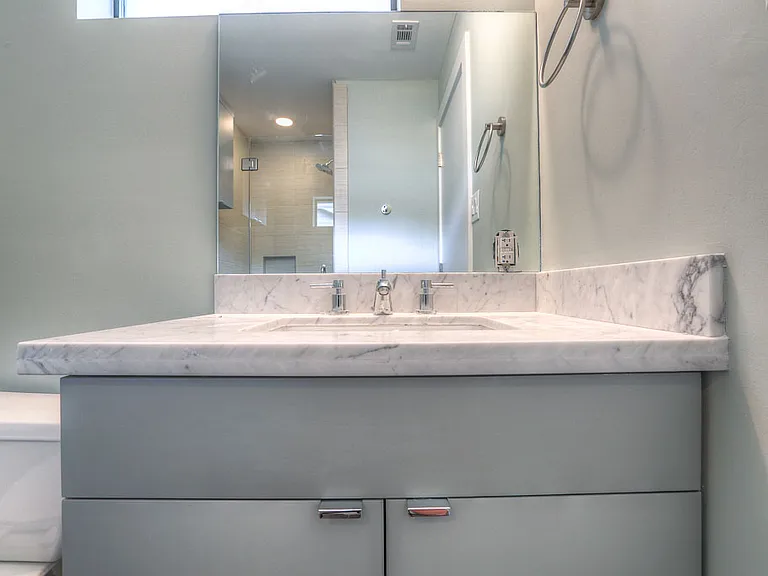 Powder/secondary bath with Carrara marble vanity, soft gray cabinetry, and large height mirror