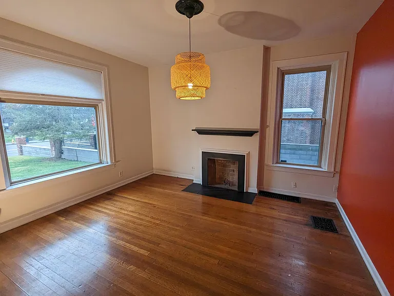 Beautiful front bedroom/dining room with original walnut hardwood floors, a non-functional fireplace, and a large closet and built in bookshelf.