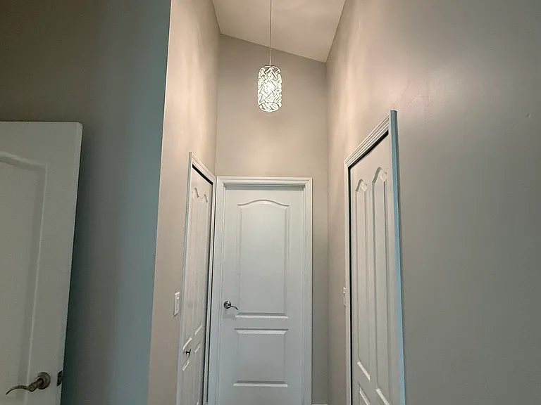 Master Suite hallway. Door to left leads to great room. bathroom door is straight ahead. 2 walk in closets on either side of the new crystal pendant light!