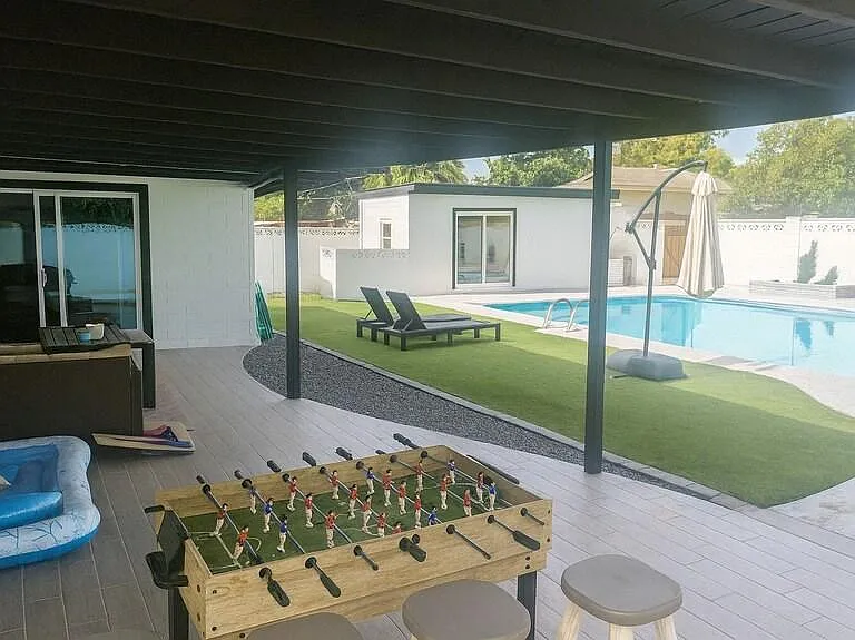 Covered patio opens to a private pool area with lounge seating, turf yard space, and room for outdoor entertaining.