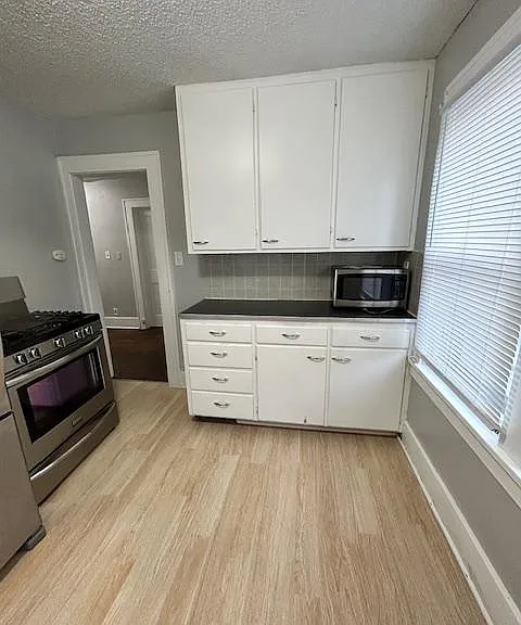 Facing the west side of kitchen. Gas stove. The doorway leads to the central hallway that connects the bedrooms and bathroom.