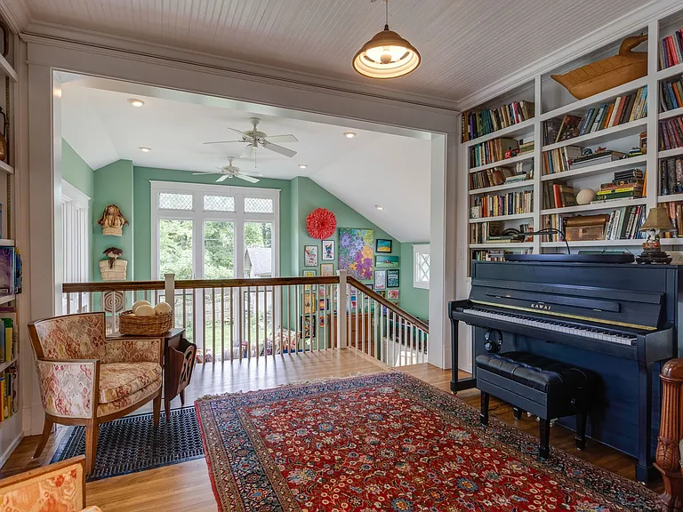 Music room with piano, built-in shelving, and access to the upper-level living area.