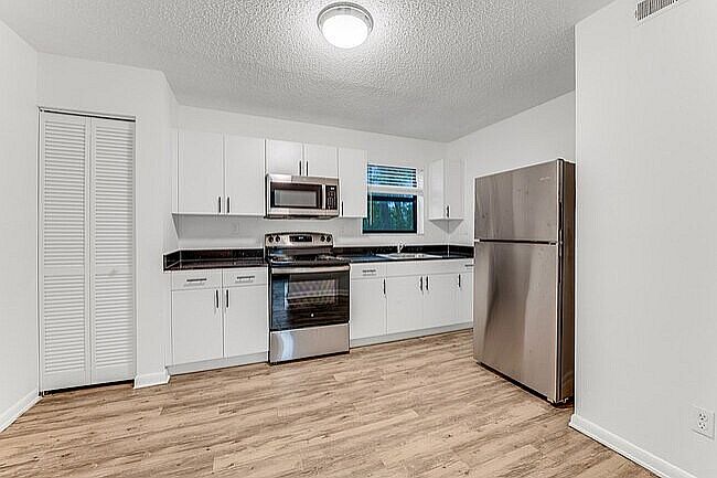 Sleek modern kitchen with stainless steel appliances, elegant white cabinetry, and warm wood flooring.
