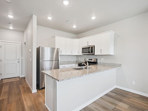 The kitchen has stainless steel appliances and plank flooring.
