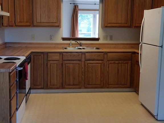 Oak kitchen includes stove, fridge and dishwasher. Pass-through lets you see into living room.