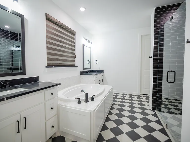 Primary Bathroom with tile patterned floors, a stall shower, two vanities, and a bath
