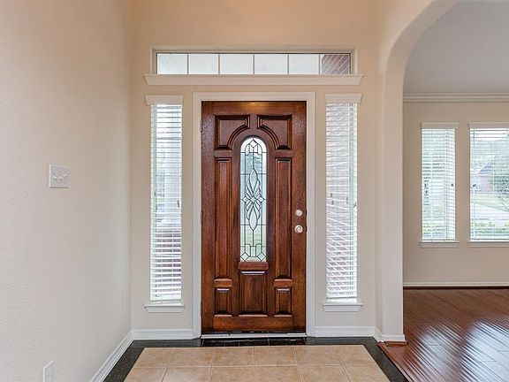 The entry way has high ceilings and handsome, banded tile flooring. The front door is beautiful and the side panels and transom window above allow for the area to be filled with natural light.