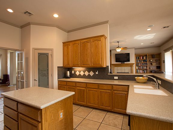 Generous Kitchen boasts solid surface counter tops and sink, chrome fixture, 18 inch tile floors, walk in pantry and center island with pull out drawers.