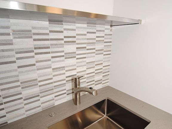 Limestone backsplash, quartz countertops, large stainless steel sink with push button garbage disposal.