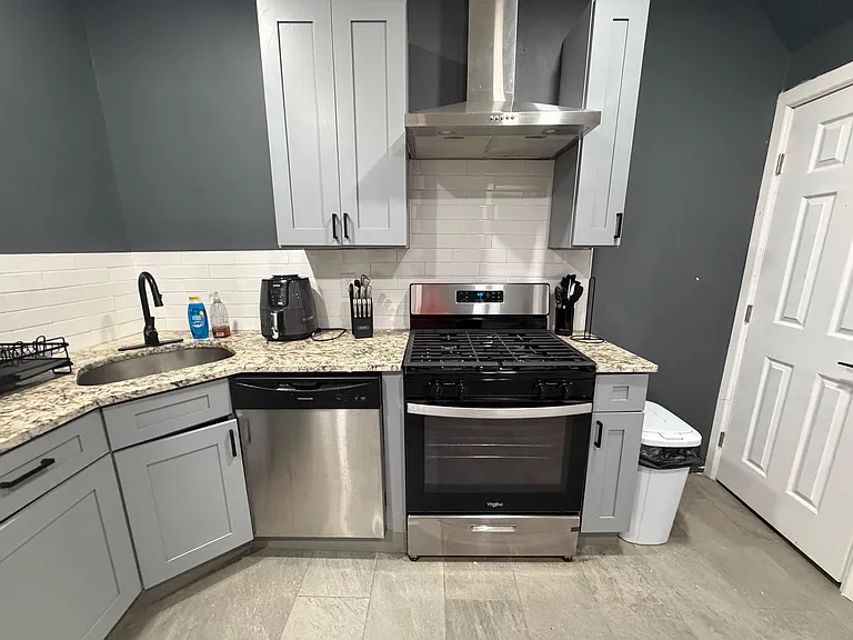 Updated kitchen with stainless steel range and hood, subway tile backsplash, and ample shaker cabinetry with stone-look count