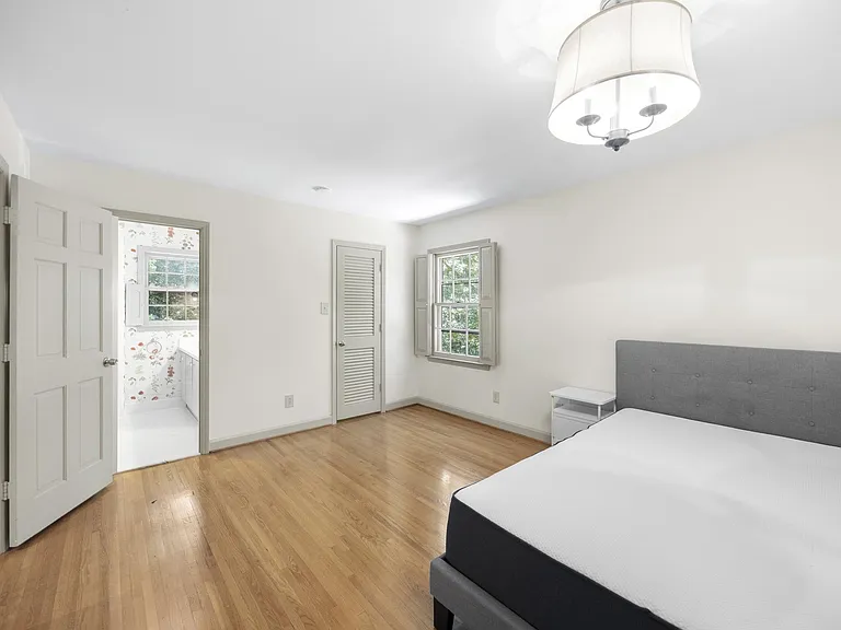 Spacious bedroom with hardwood floors, ample wall space, and a large window plus closet storage for everyday ease.