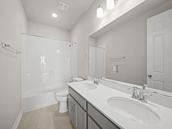 Spacious second bathroom offering a dual-sink vanity with gray cabinets, light countertops, and a sh