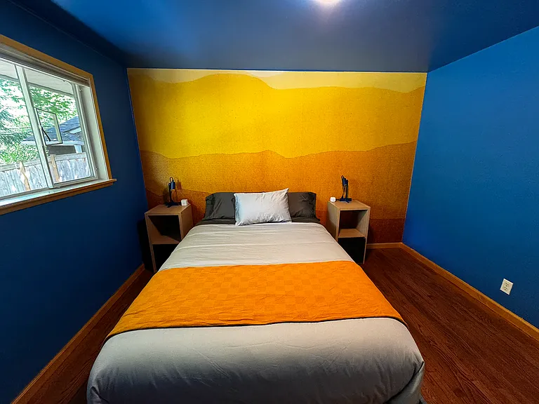 Bedroom 3 furnished with a queen bed, side tables and a closet. It is across from the main bathroom and share the same hallway as bedroom and 2 (currently occupied)