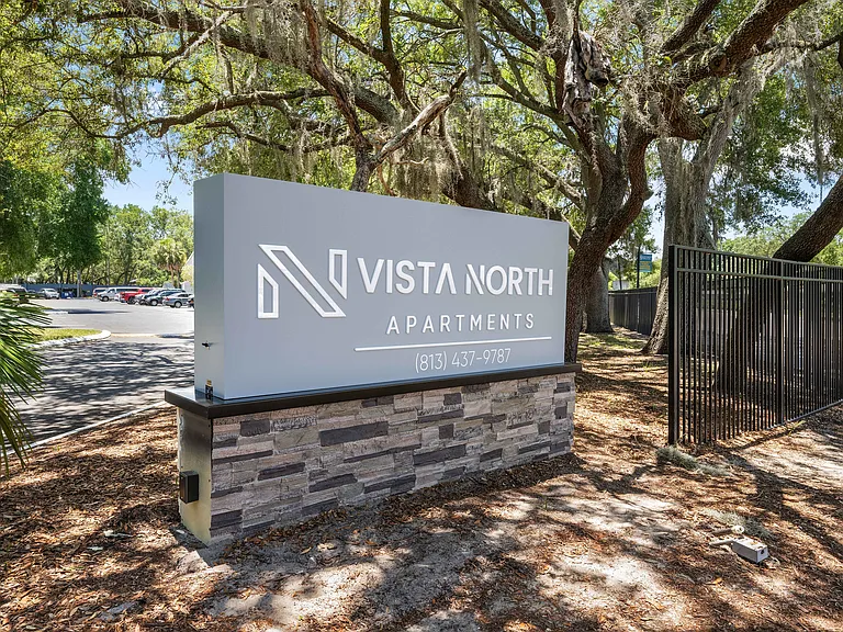 Welcome to Vista North Apartments, featuring elegant signage surrounded by lush greenery and inviting natural landscapes.