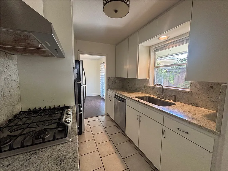 Kitchen featuring white cabinetry, light-toned granite countertops, a stainless steel gas range, and an undermount sink with a gooseneck faucet