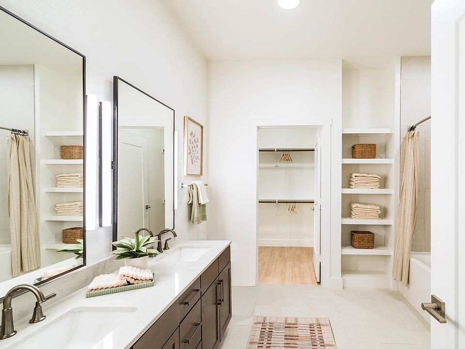 Spacious primary baths at Modera Trailhead feature dual vanities, open shelving, and seamless access to oversized closets.