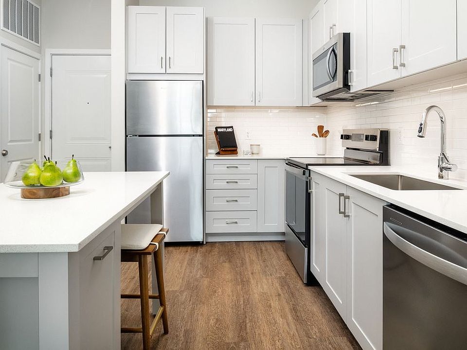 New West Phase apartments - Finish Package III Kitchen with stainless steel appliances, white quartz countertops, grey cabinetry, and hard surface flooring