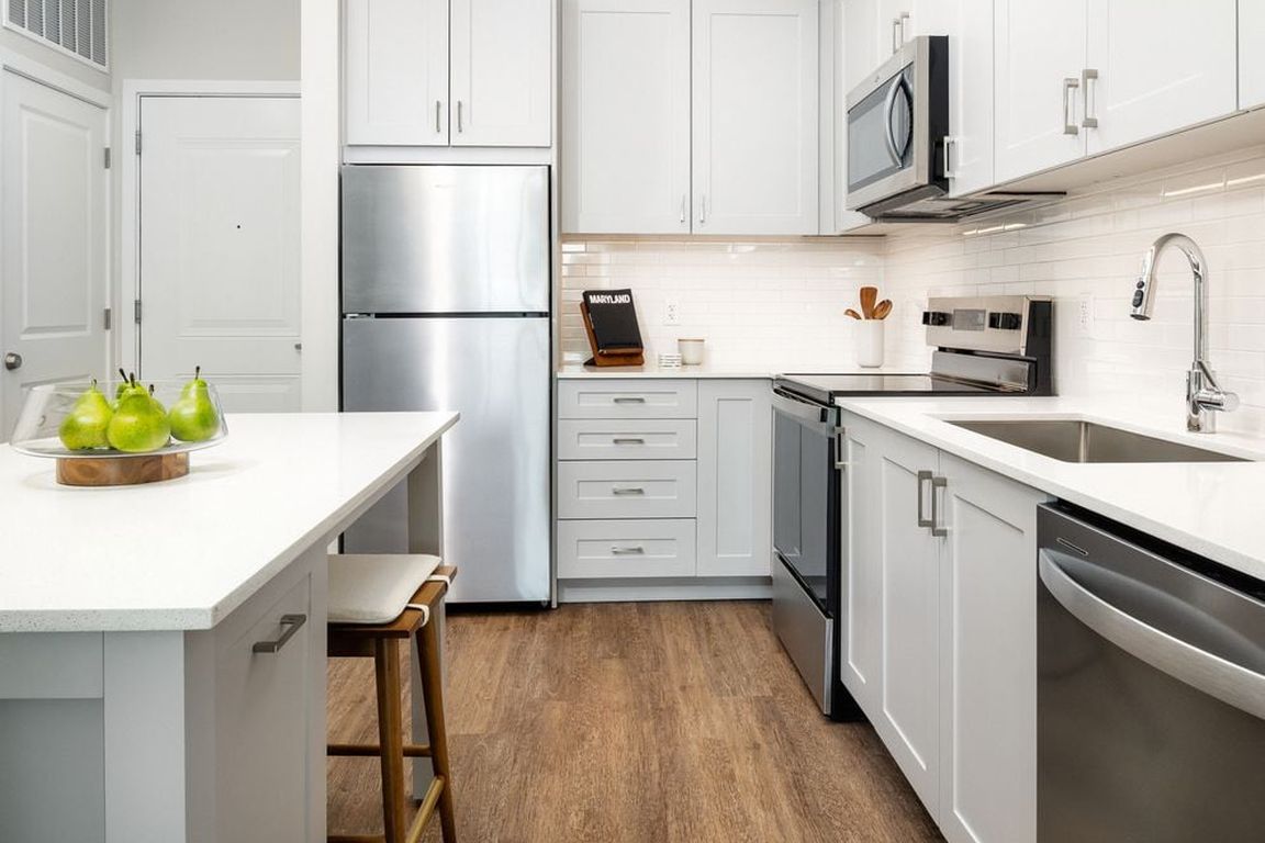New West Phase - Finish Package III Kitchen with stainless steel appliances, white quartz countertops, grey cabinetry, and hard surface flooring