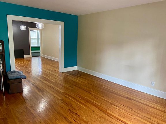Unfurnished living room looking into dining area. Main Bedroom #1 door open in background. Wood floors.