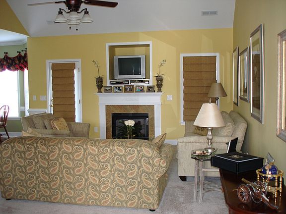Great room has vaulted ceiling, open floorplan and custom roman shades.