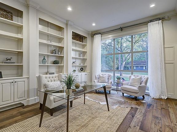 Upon entering , this Formal Living Room or oversized Den/Study/Home office is richly appointed with floor to ceiling windows, shelving, storage, hardwoods, and detailed custom paneling.