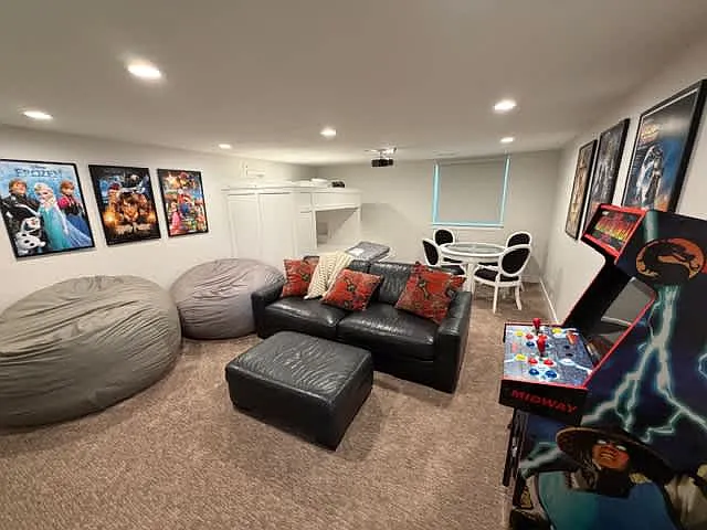 Entertainment room with movie projector, arcade games, bean bags, table, and bunk beds.