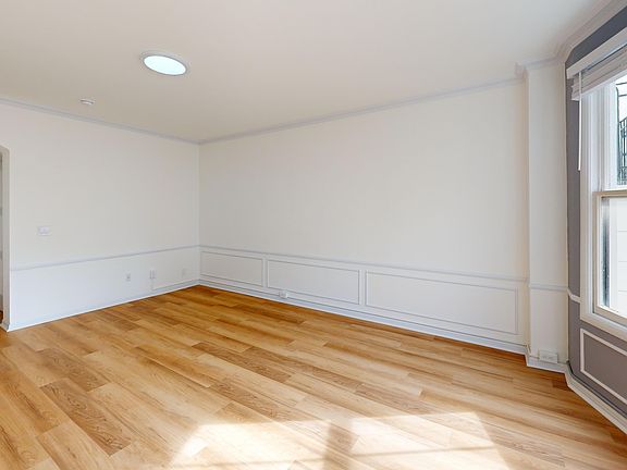 Bright, spacious room featuring wood flooring and a large window