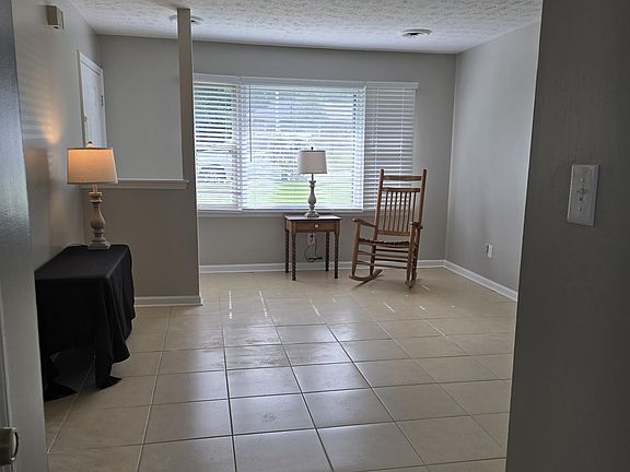 View of front entrance/window; bomb proof cream tile flooring in living room, hallway, and bathroom; neutral, warm wall color (newly painted "Agreeable Gray").