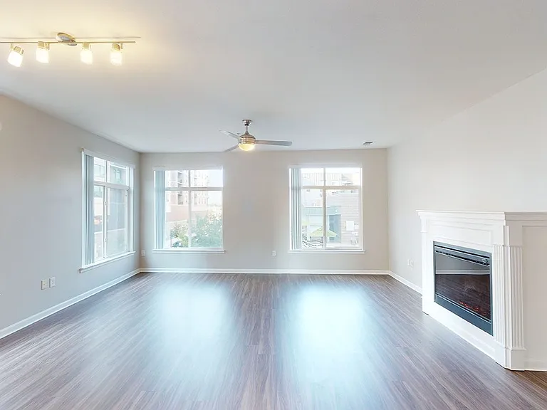 Apartment living room with wood-style flooring and fireplace in select homes.