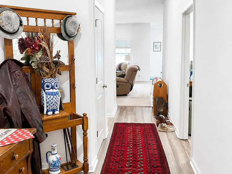 Long entry hallway with durable flooring, overhead lighting, and convenient coat storage leading into the main living area.