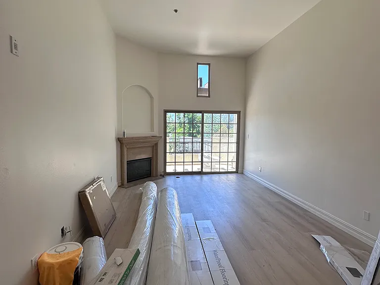Living room with fireplace & high ceilings.