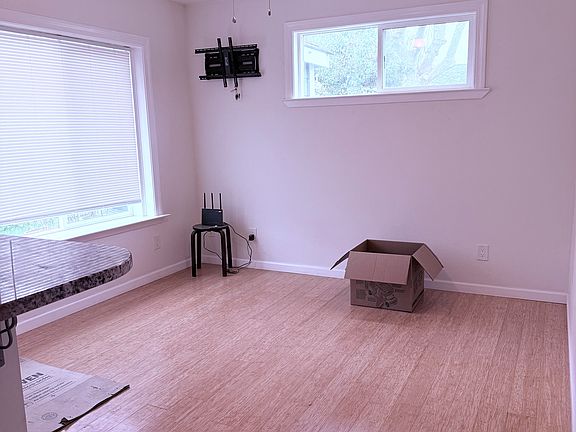 Front living area with lots of light, wood floors, ceiling fan, and a nice big front window with the perfect sill for plants or a lounging cat