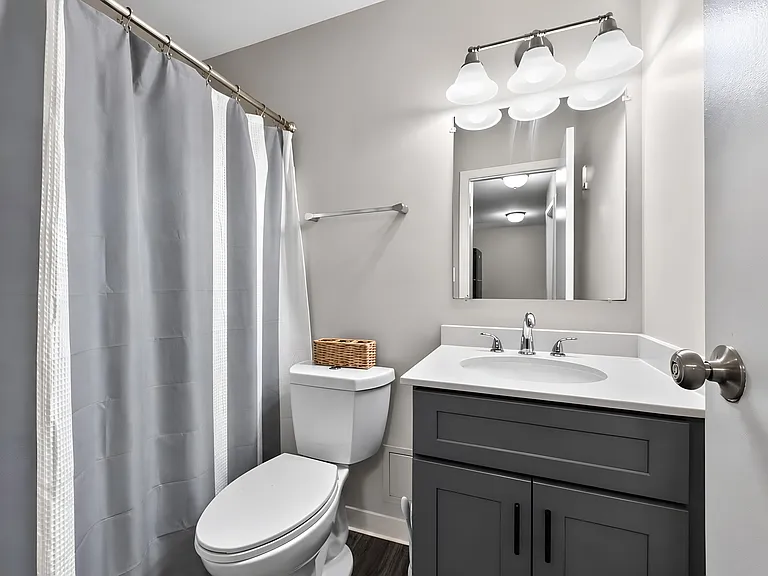 Enjoy a clean, modern bathroom featuring crisp white fixtures and a sleek grey shower curtain at Renaissance at Carol Stream in Carol Stream, IL.