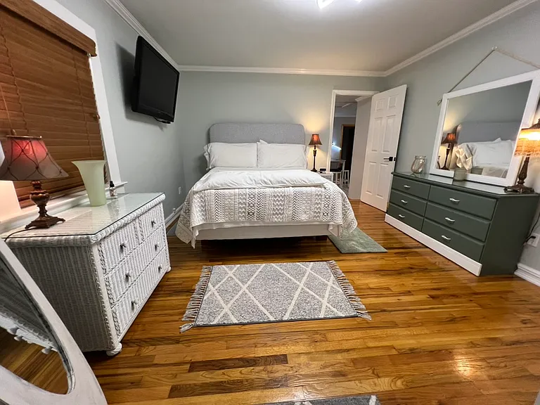 16x12 large bedroom. Queen bed with comfy topper. Loads of king pillows. Cushioned headboard. Full length mirror. Wall mounted 42 inch Vizio smart TV. Two dressers with lots of drawers. LED ceiling light with fan. Hardwood floors with lovely rugs. Lamps.