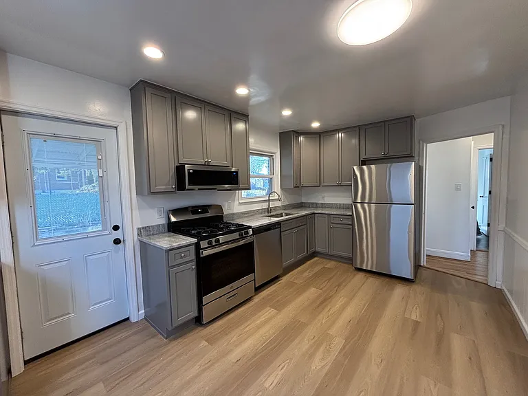 Completely renovated kitchen. New floor, cabinetry, and stainless steel appliances. Door to backyard.