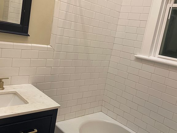 bathroom with subway tiles brazil hardwood floor, new dark blue vanity with matching fog free mirror and gold fixture. (I still need to clean and recaulk the tub in this photo)
