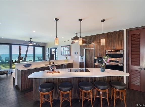 The ocean home's kitchen opens to the interior and features built-in appliances, a large island, and has beautiful ocean views.