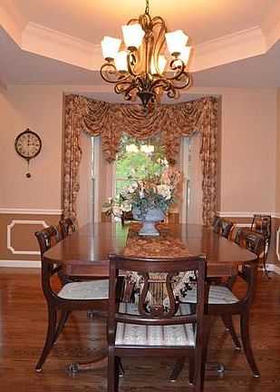 Floor to ceiling bay window in Dining Room with custom drapes brings in natural light!