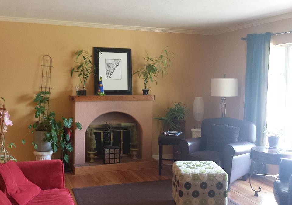 Living room with wood-burning fireplace, hardwood floors, and a large picture window (draperies included) with western exposure.