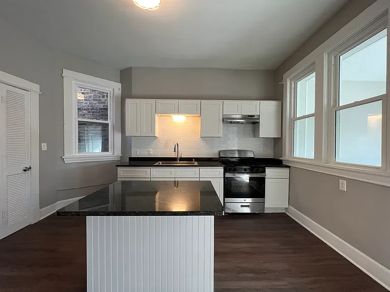 Newly renovated kitchen with granite countertops, crisp white cabinets, brand new stainless steel appliances, food pantry, and island which opens up to the den space.